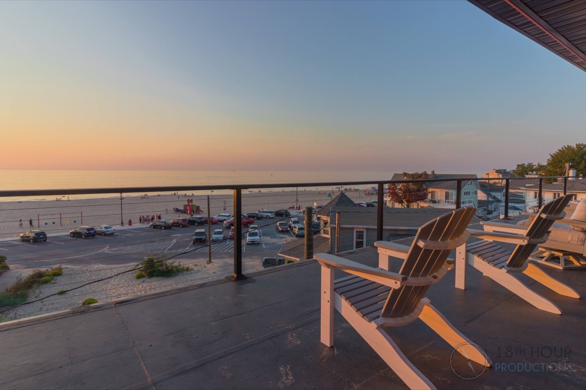 Adirondack chairs on a deck overlooking Lake Michigan at sunset